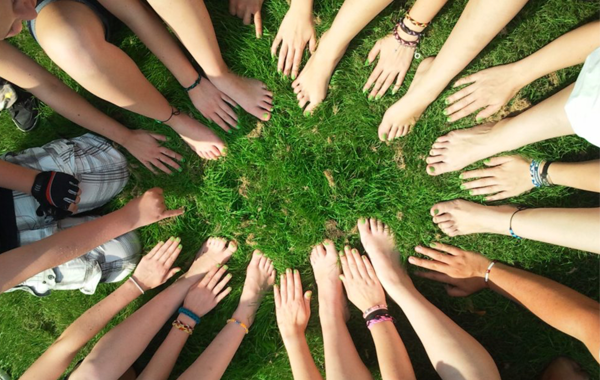 hands and feet in a circle on grass