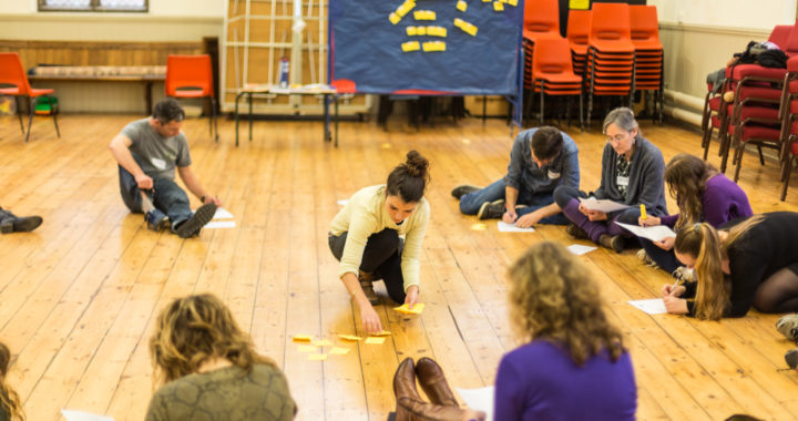 a group of people sitting on a wooden floor writing down ideas