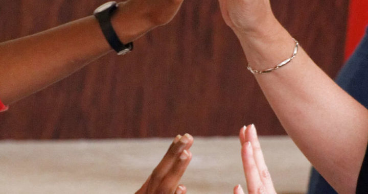two sets of hands of people from different races reaching and mirroring each other